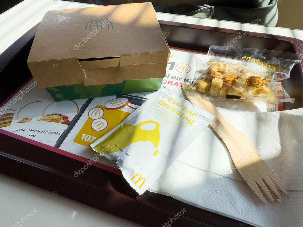 Fast food meal with caesar salad box and dressing on tray.