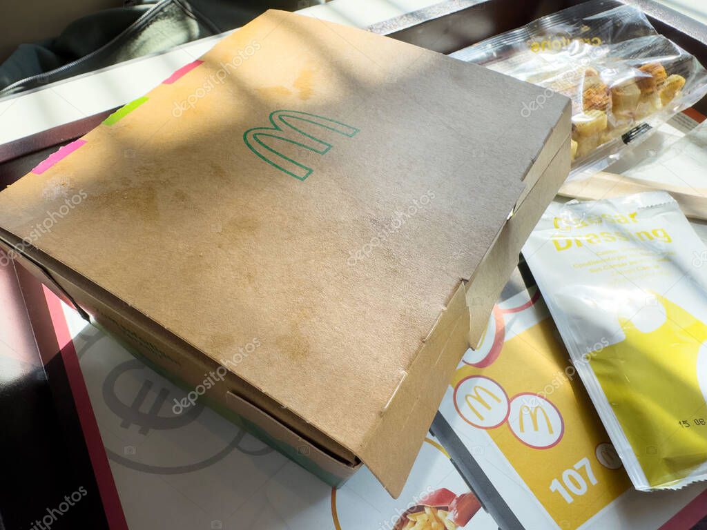 Fast food packaging with burger box and caesar dressing on table.