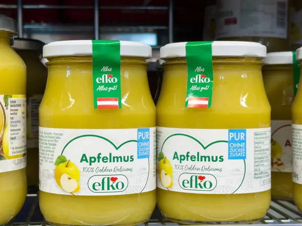 Süpermarket rafında yeşil etiketli elma sosu kavanozları ve Almanca metinler..