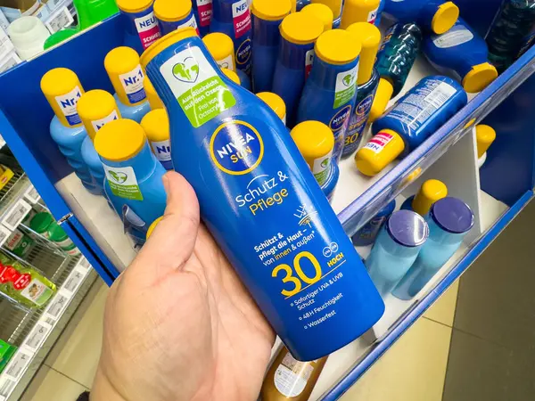Kafkas erkek eli Nivea güneş kremi şişesini çeşitli ürünlerle sergiliyor..