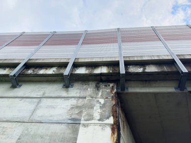 Paslı beton köprü ve bulutlu bir gökyüzünün altında metal korkuluklar..