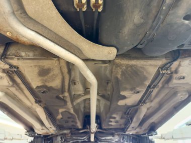 Garajda asansörde metal egzoz sistemi olan bir aracın alt görüntüsü..