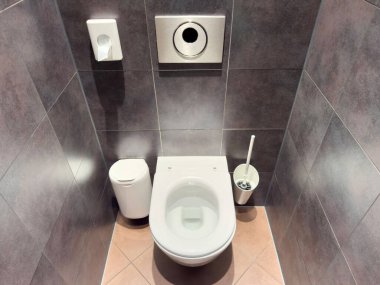 Duvara monte edilmiş sifonu ve fayanslı tuvaleti olan modern umumi tuvalet..