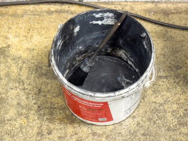 Beton yüzeyinde fırçası olan boş boya kovası.