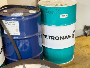 Garaj düzeninde petronas logosu olan mavi ve deniz mavisi yağ varilleri..