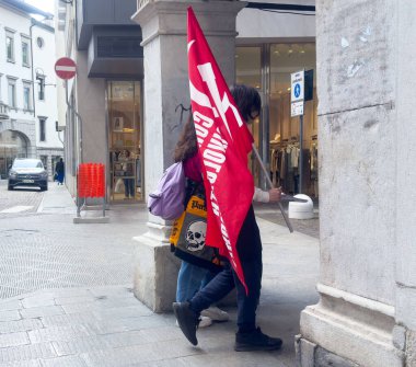 Sokak protestolarında kırmızı bayrakla yürüyen genç yetişkinler.