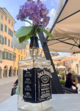 Avrupa kafe masasında Jack Daniel 'ın şişe vazosunda leylak buketi..