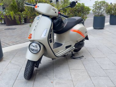 Kentsel caddede turuncu çizgili modern bej scooter..