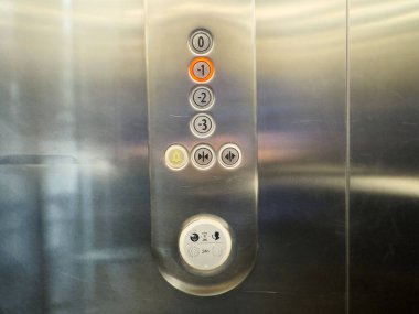 Döşeme düğmeleri ve sembolleri olan metal asansör kontrol paneline yakın çekim.