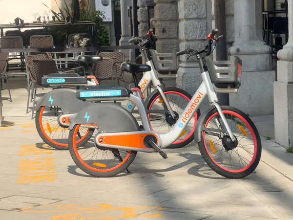 Şehir sokağına park etmiş güneş ışığı gölgeli elektrikli bisikletler..