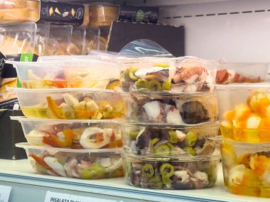 Süpermarketteki plastik kaplarda taze deniz ürünleri salatası..