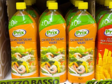 İtalyan prix karışık tohumlu yağ şişeleri ile süpermarket raflarında sarı kapaklar.
