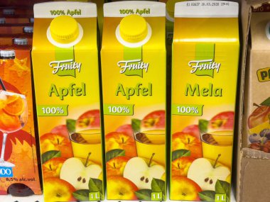 Elma suyu kutuları süpermarket koridorunda çok dilli etiketlerle görüntülenir.