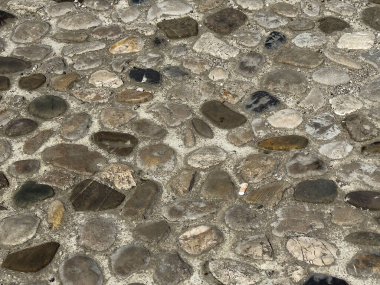 Çakıl taşı kaldırımları nötr tonlarda çeşitli taşlarla desenlendirilmiş..