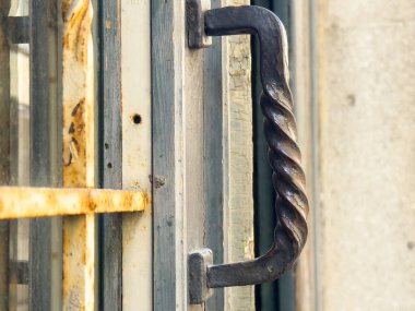 Yıpranmış ahşap çerçevede eğri büğrü metal kapı kolu..