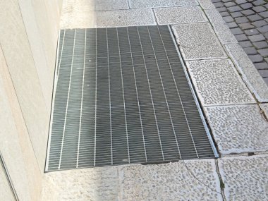 Şehir kaldırımı ızgarası ve desenli taş kaldırım gün ışığında.
