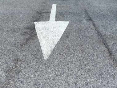 Asfalt yolda beyaz ok yön hareketi sinyali veriyor.