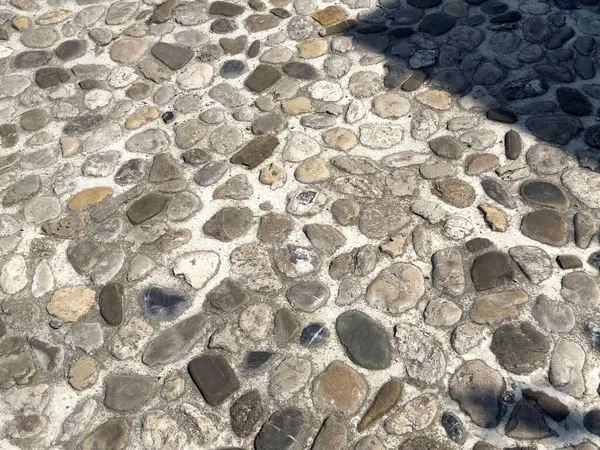 Güneş ışığının altındaki kaldırım taşı yolu ve desenli taşların gölgesi..