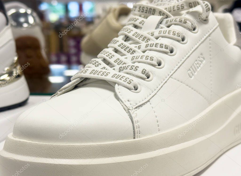 White guess sneakers with branded laces on display in store.