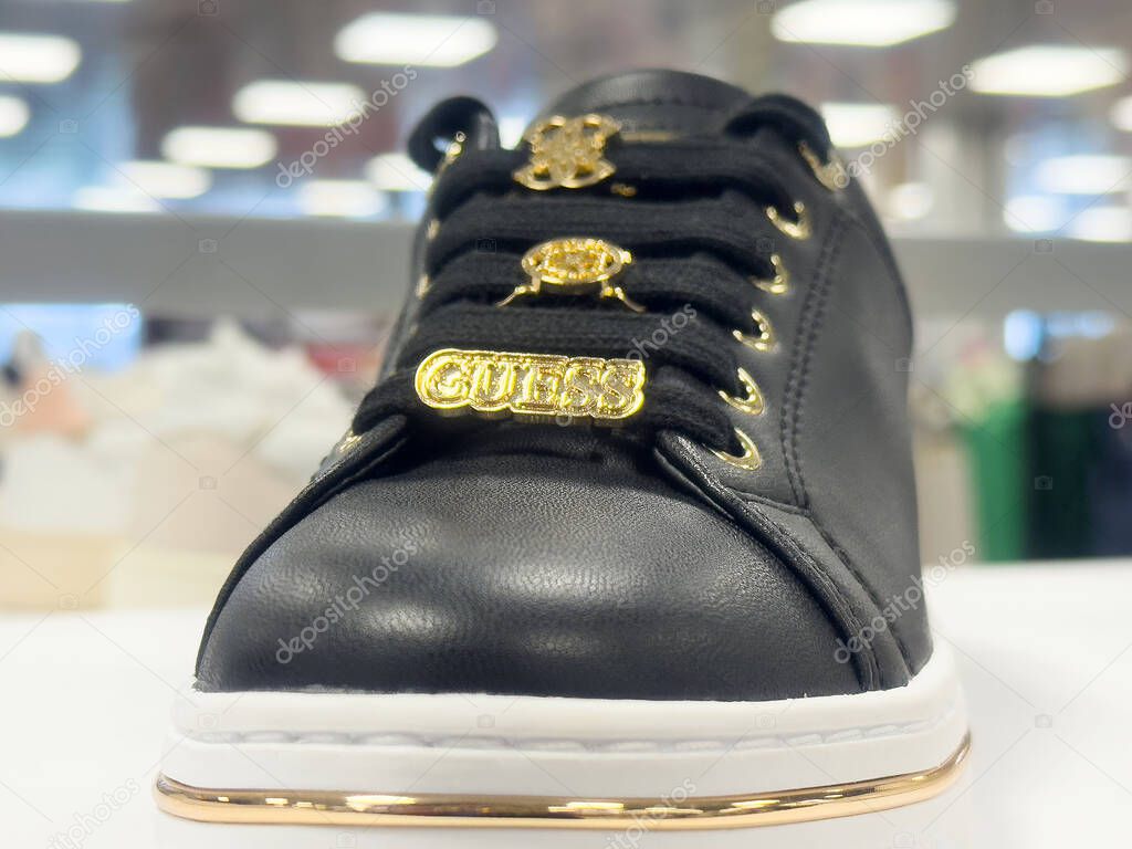 Black leather sneaker with gold accents and brand details.