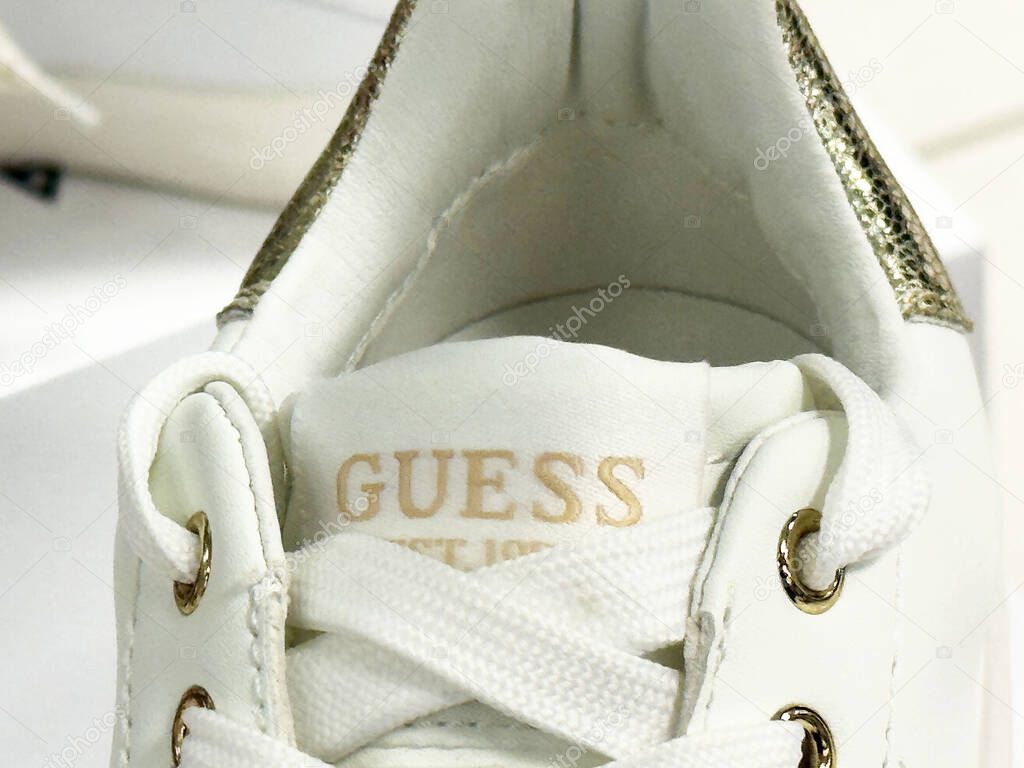White guess sneakers with gold accents and laces.