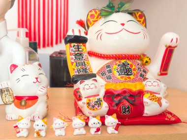 Japon şanslı kedi heykelcikleri kırmızı dekor aksanlı raflarda sergilenir.