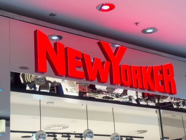 Modern kapalı alışveriş merkezinde parlak kırmızı New Yorker mağaza tabelası.