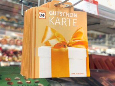 Perakende mağazasında turuncu ve beyaz tasarımlı hediye çeki gösterimi.