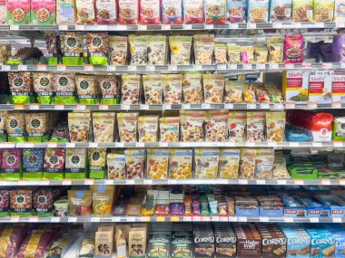 Renkli paketlerde çeşitli kurutulmuş meyve ve fındıklı süpermarket rafı.