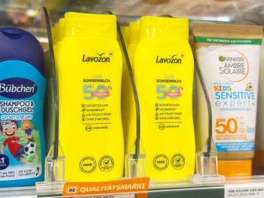 Parlak sarı güneş kremi şişeleri 50 numaralı spf etiketli mağaza rafında..