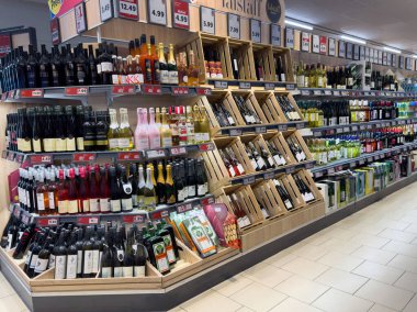 Süpermarket şarap ve içecek reyonu ahşap raflarda çeşitli şişe çeşitleri ile.