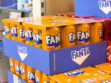 Mağaza rafındaki mavi ambalajda portakallı soda kutularının görüntüsü.