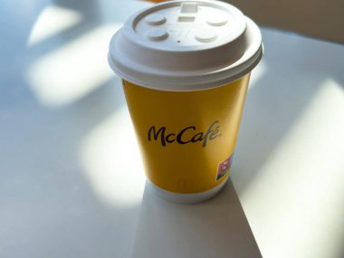 McDonald 's McKafe kahve fincanı güneşli masada, parlak logo ve kapaklı..