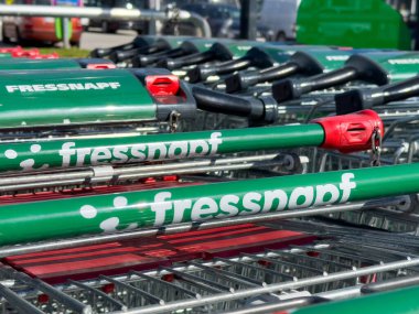 Marketin önünde arka arkaya yeşil alışveriş arabaları..