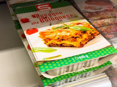 Donmuş lazanya paketi süpermarket koridorunda sergileniyor.