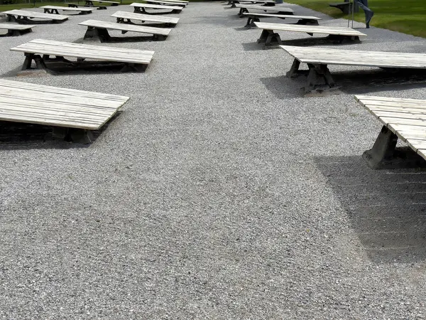 Parktaki çakıl yolunda boş ahşap masalarla dışarıda piknik yapmak..