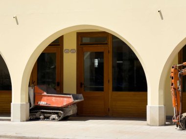 Kemerli binanın altına park edilmiş kompakt inşaat aracı..