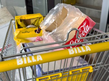 Billa mağazasında boş kola kutusu ve abur cubur paketleri olan market arabası..