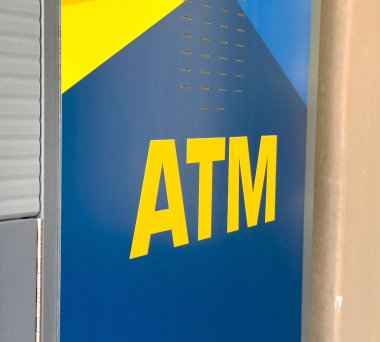 Şehir ortamında sarı ve mavi desenli modern ATM makinesi.