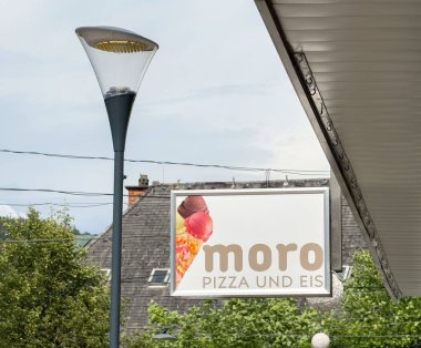 Şehir sokaklarında sokak lambasıyla Moro Pizza ve Eis için açık hava tabelası..