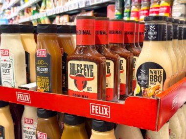 Marketin rafında bulunan çeşitli bbq sosları, hedef tahtası ve Felix markaları içeriyor..