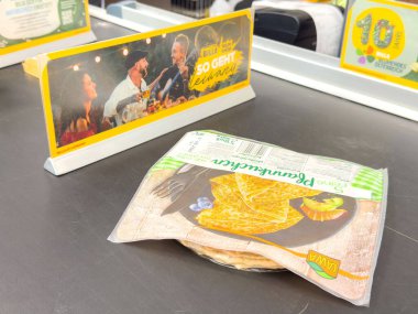 Süpermarket taşıma bandında reklam ekranlı paketlenmiş gözlemeler.