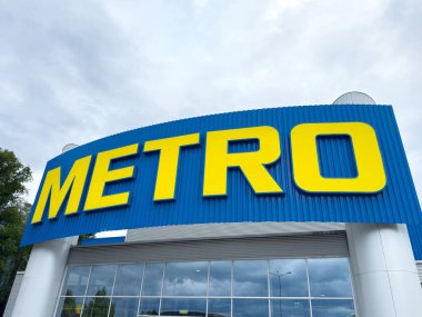 Bulutlu gökyüzüne karşı mavi ve sarı metro vitrinleri.