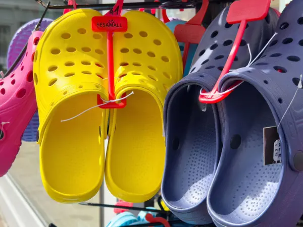 Mağaza rafında sarı ve mavi ayakkabılar sergilenen renkli takunyalar.