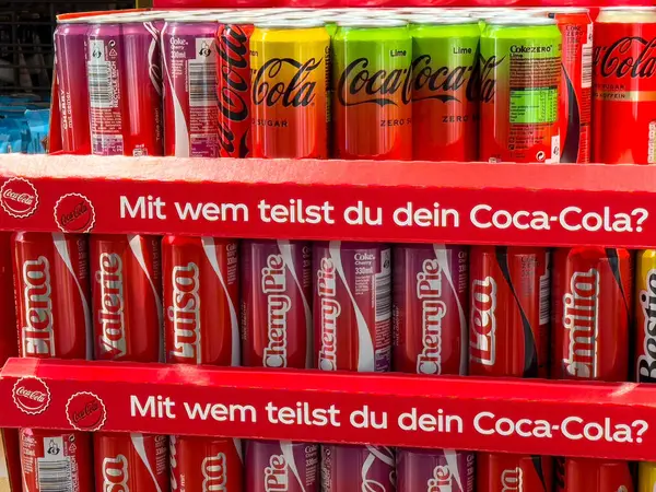 Almanca metin içinde kişiselleştirilmiş isimler ve tatlar içeren renkli coca-cola görüntüsü.