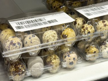 Barkod ve fiyat etiketleriyle sergilenen raflarda plastik kutular içinde bıldırcın yumurtaları.