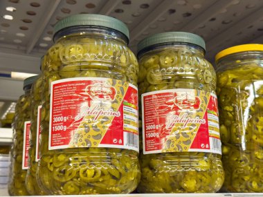 Süpermarket raflarında dilimlenmiş jalapenoların olduğu kavanozlar..