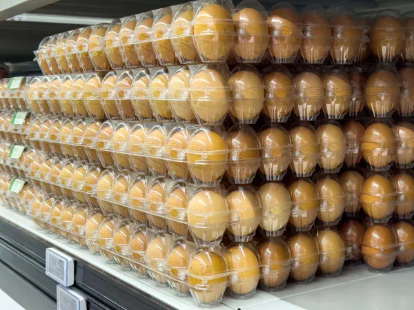 Bir mağazanın rafında şeffaf karton içinde kahverengi yumurta yığınları.