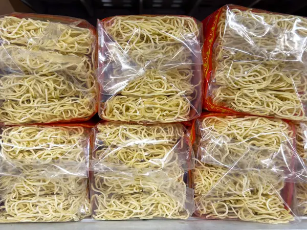 Plastik ambalajda paketlenmiş kuru erişte yığınları.