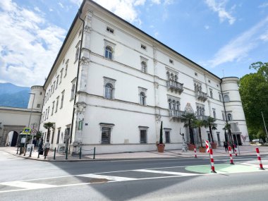 Güneşli bir kentsel alanda köşe sokakta mimari detaylara sahip tarihi beyaz bir bina..